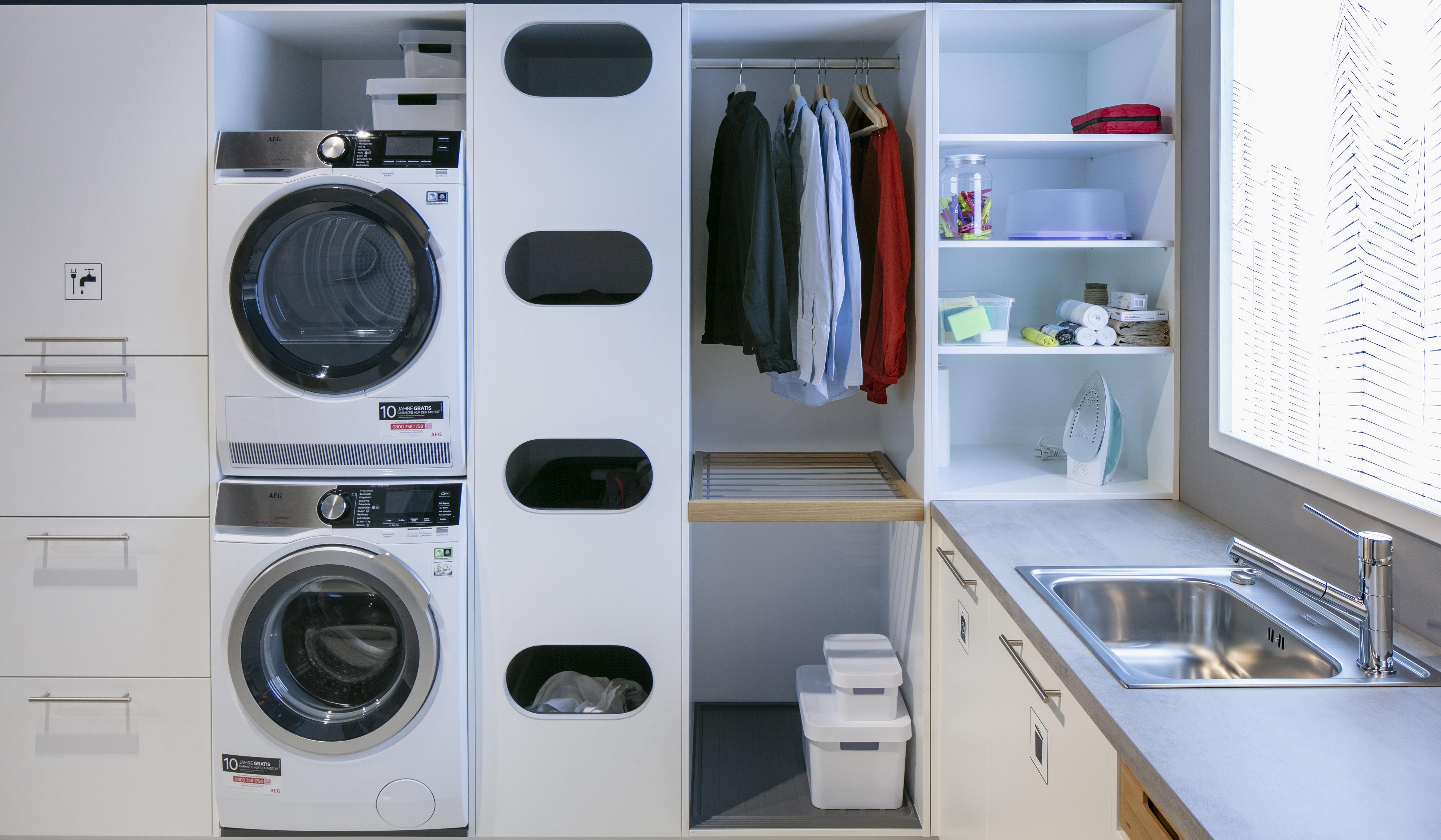 Hauswirtschaftsraum mit Waschmaschine und Trockner übereinander und Spülbecken Möbel von Schüller Küchen